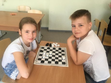 Школьники с удовольствием проводят время за шашечной доской